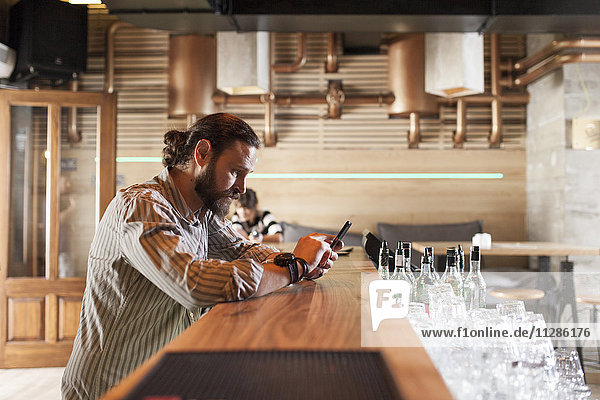 Man at bar counter in coffee shop using smart phone