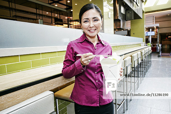 Smiling Japanese businesswoman posing in food court