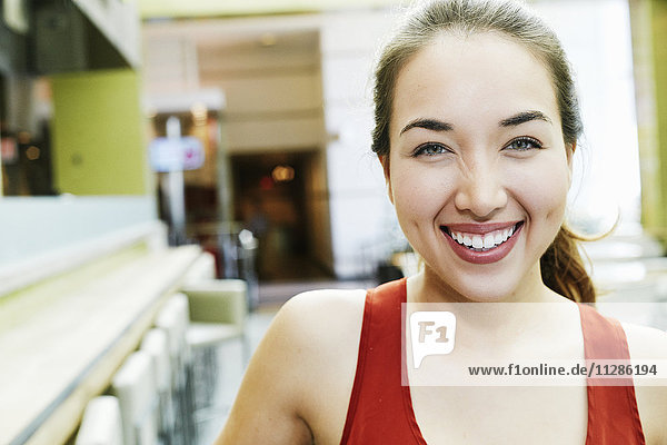 Lächelnde gemischtrassige Frau posiert im Food Court