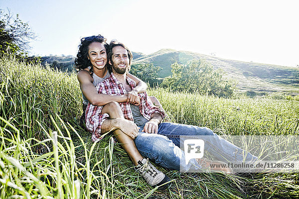 Portrait of smiling couple hugging on hill