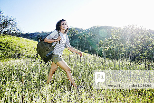 Smiling Mixed Race woman hiking on hill