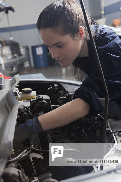 Hispanic mechanic repairing car engine