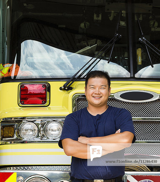 Lächelnder chinesischer Feuerwehrmann posiert mit Feuerwehrauto
