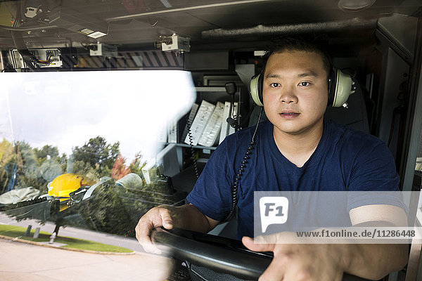 Chinesischer Feuerwehrmann mit Kopfhörern am Steuer eines Feuerwehrautos