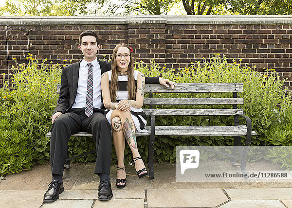 Gut gekleidetes kaukasisches Paar sitzt auf einer Bank im Park