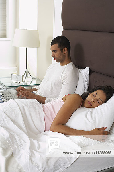 Ehepaar im Bett  Mann mit Laptop