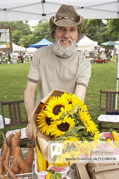 Mann bietet Blumen auf dem Bauernmarkt an