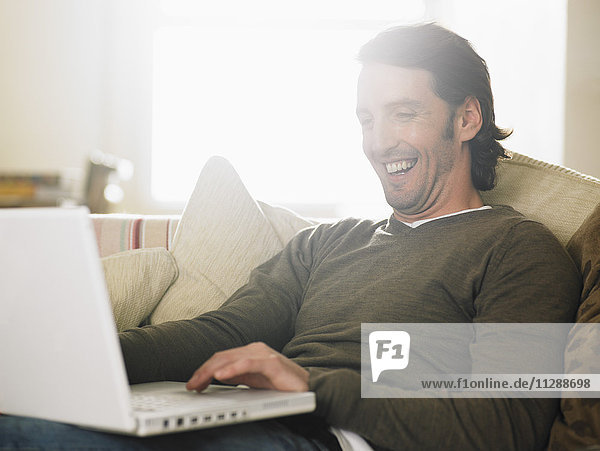 Porträt eines auf dem Sofa sitzenden Mannes mit Laptop-Computer