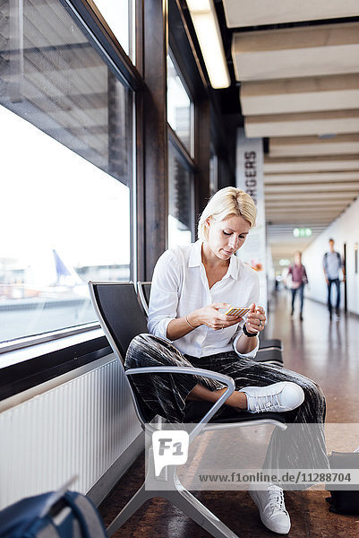 Frau benutzt Mobiltelefon am Flughafen