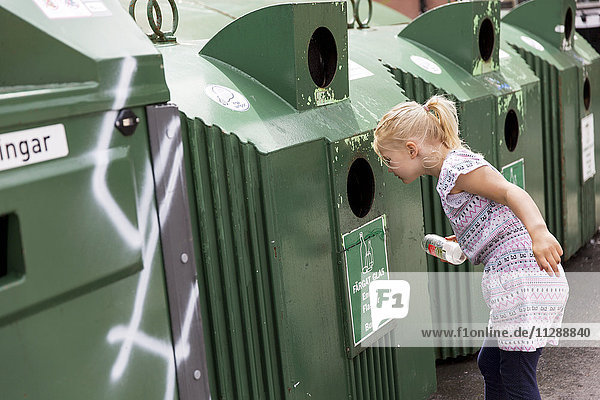 Mädchen schaut in die Recycling-Tonne