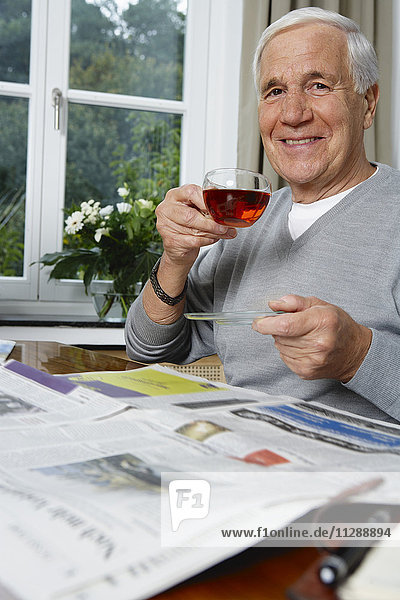 Mann trinkt Tee und liest Zeitung