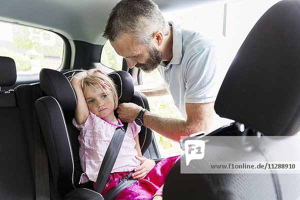 Father buckle girl in car