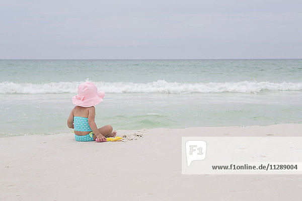 Rückenansicht eines kleinen Mädchens mit Sonnenhut am Strand und Blick auf den Ozean  Destin  Florida  USA