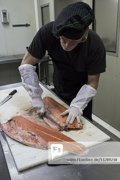 Fischraucher bereitet Lachs zum Räuchern vor