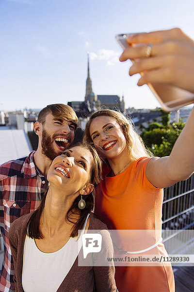 Österreich  Wien  drei Freunde auf der Dachterrasse mit Stephansdom im Hintergrund