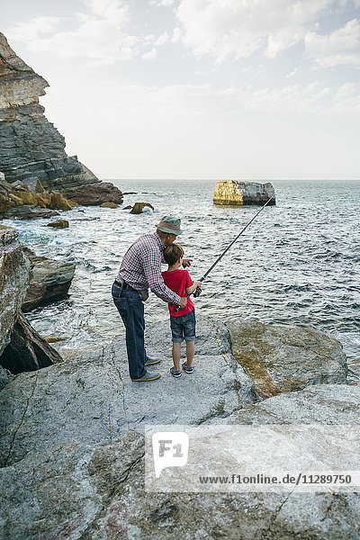 Grandfather and grandson fishing together at the sea