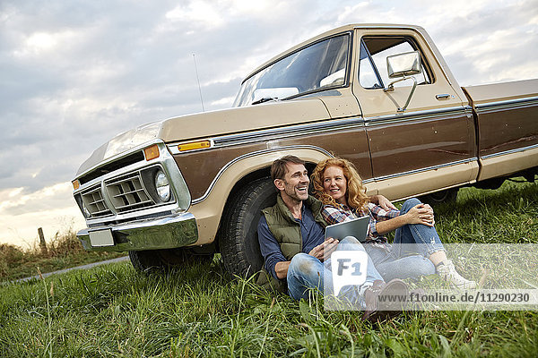 Couple sitting at pick up truck with tablet