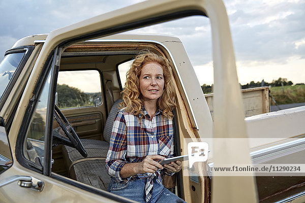 Frau benutzt Tablette am Pick-Up-Truck