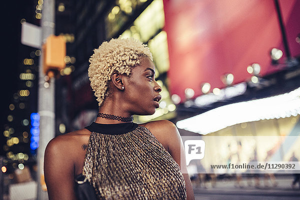 USA  New York City  junge Frau am Times Square bei Nacht etwas beobachtend