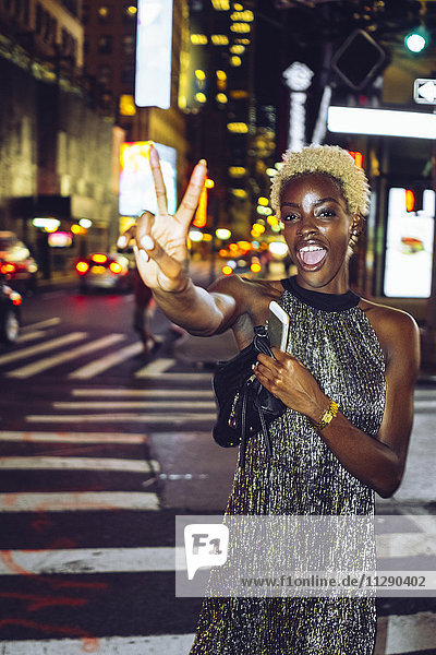 USA  New York City  junge Frau mit Siegeszeichen am Times Square bei Nacht