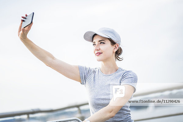 Frau mit Basecap  die Selfie mit Handy nimmt
