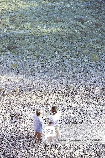 Draufsicht des Seniorenpaares  das Hand in Hand am Strand steht.