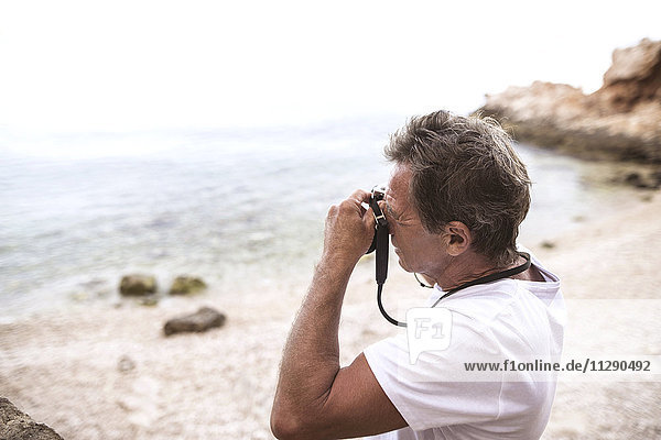 Senior Mann beim Fotografieren am Strand
