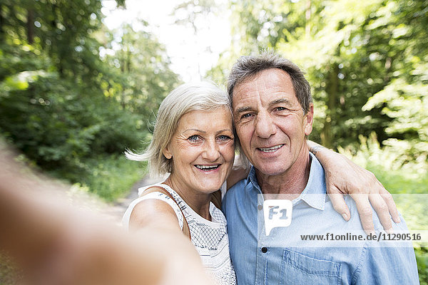 Happy senior couple taking selfie in the woods