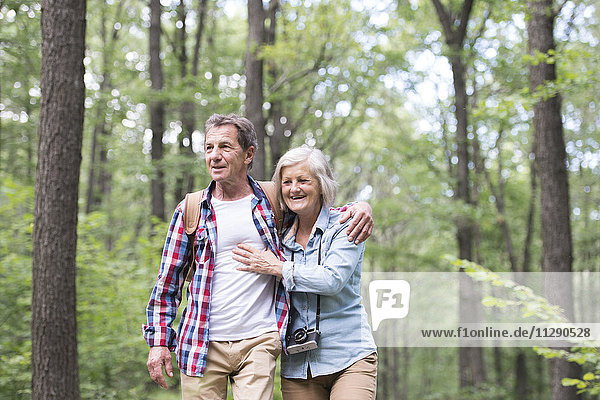 Happy senior couple walking arm in arm in the woods