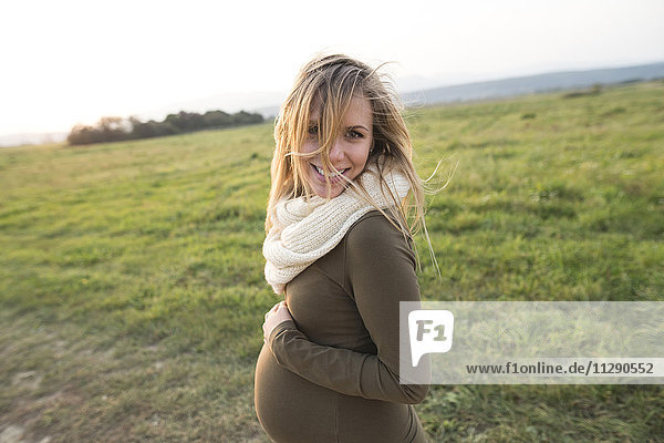 Smiling pregnant woman in rural landscape