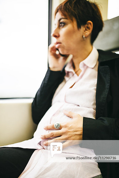 Schwangere Frau im Zug auf dem Handy