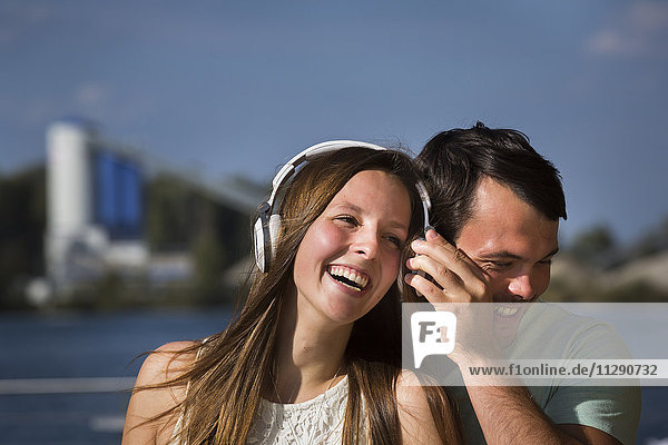 Glückliches junges Paar  das sich Kopfhörer teilt