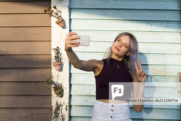 Junge Frau mit gefärbtem Haar  die einen Selfie nimmt.