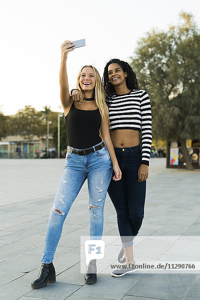 Zwei junge Frauen  die einen Selfie auf dem Platz haben.