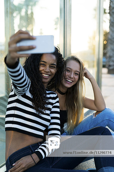 Zwei junge Frauen  die mit einem Selfie nach draußen gehen.
