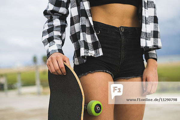 Frau mit Skateboard in schwarzer Hot Pants  Teilansicht