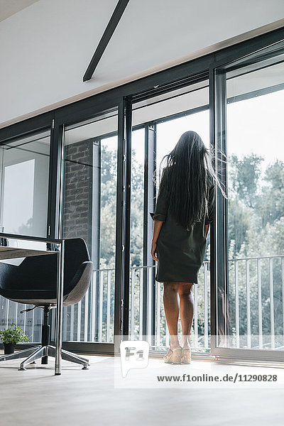 Woman with long grey hair looking out of window