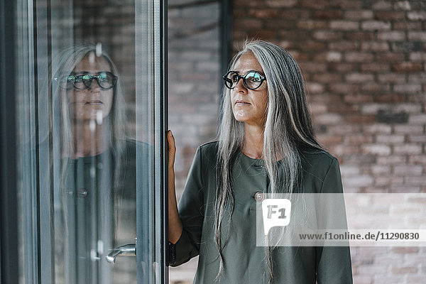Woman with long grey hair reflected in window