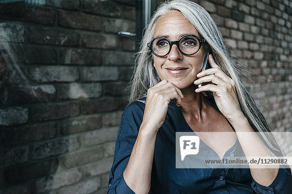 Smiling woman with long grey hair on cell phone