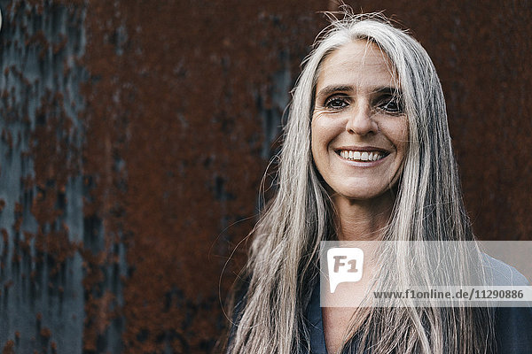 Porträt einer lächelnden Frau mit langen grauen Haaren