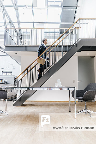 Geschäftsmann  der auf einer Treppe in einem Loft läuft.