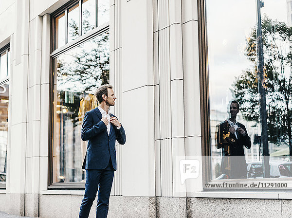 Businessman looking at his mirror image at window display