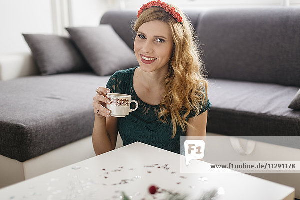 Porträt einer lächelnden jungen Frau  die zu Hause zu Weihnachten Kaffee trinkt.