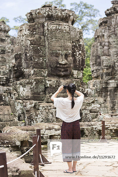 Kambodscha  Siem Reap  Angkor Thom  Rückansicht des Touristen beim Fotografieren des Bayon-Tempels