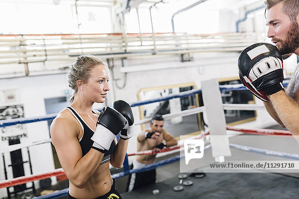 Female boxer sparring with coach