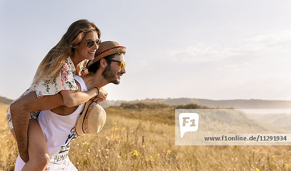 Man giving his girlfriend a piggyback ride in nature