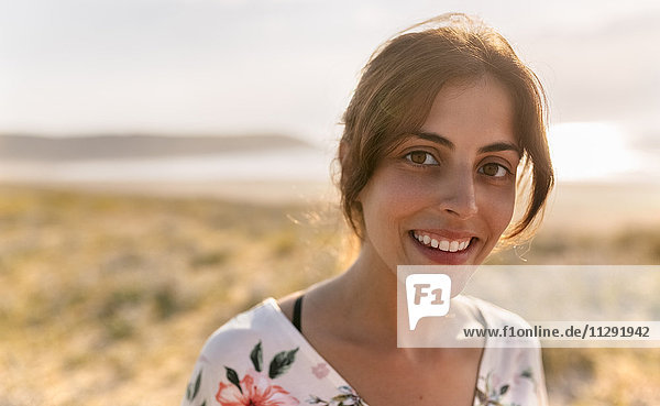 Portrait of smiling woman near the coast at evening sunlight
