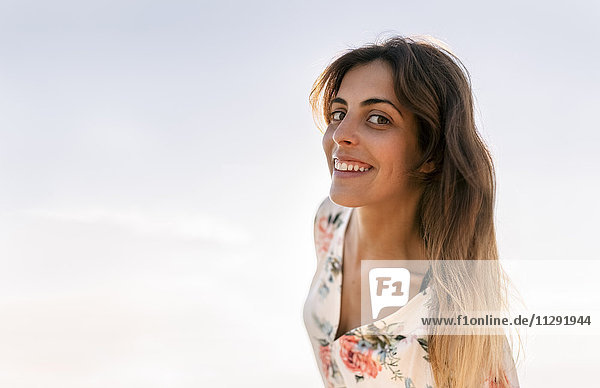 Portrait of smiling woman in front of sky at evening twilight