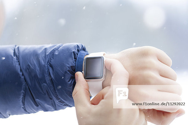 Sportlicher Mann beim Prüfen seiner Smartwatch im Winter  Nahaufnahme
