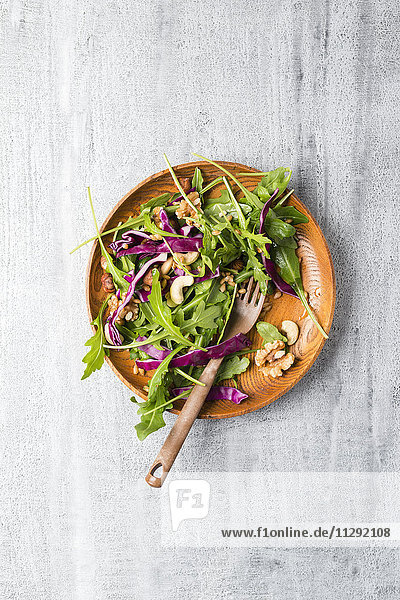 Salat mit Rotkohl  Rucola  Einkorn und verschiedenen Nüssen auf Holzplatte